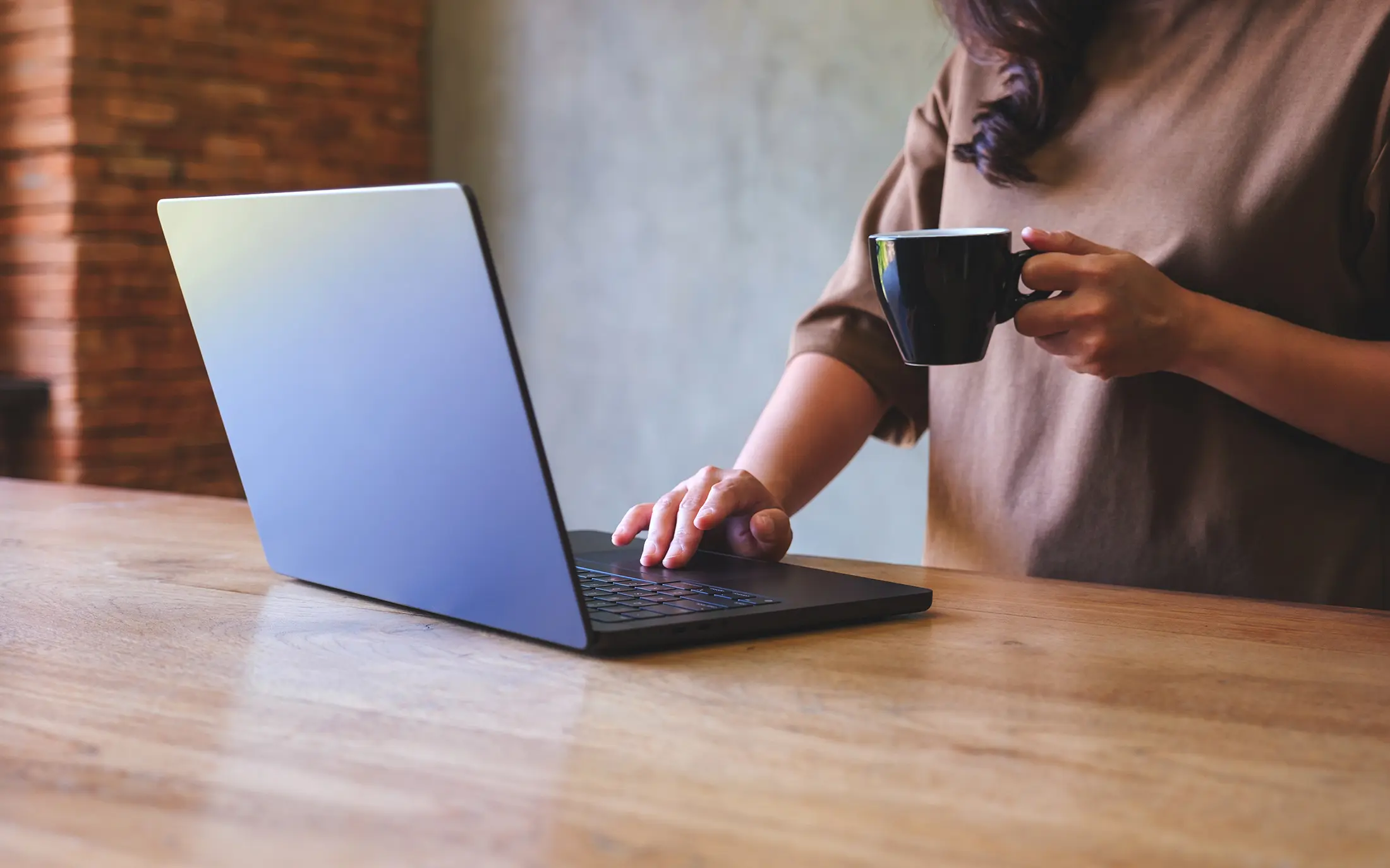 Woman drinking coffee and working on laptop